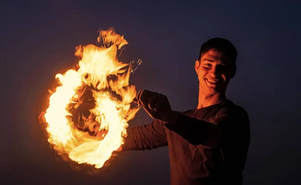 Happy guy artist perform fire circle by spinning burning poi on idyllic dark sky at night outdoors, orbital