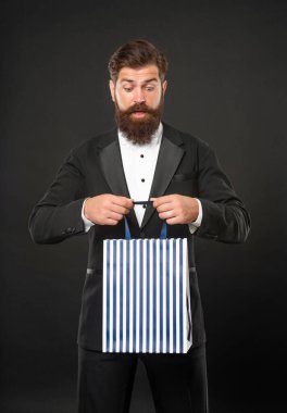 Smokinli, papyonlu, siyah arkaplanlı ve alışveriş çantalı bir adam. Boşluğu kopyala