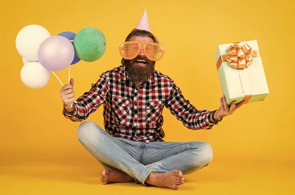 Komik, vahşi, sakallı, kareli gömlek giyen, sakallı, bıyıklı parti balonları ve hediye kutusu olan bir adam. — Stok fotoğraf
