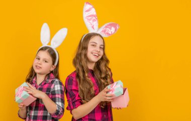 Tavşan kulaklı gülümseyen Paskalya çocukları hediye kutusunu fotokopi alanı ile sarı arka planda tutun