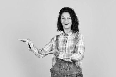 Kız ürünleri sunuyor. neşeli ve büyüleyici bir gülümseme. Öğrenci kız eğleniyor. Moda portresi güzel genç bayan. Kareli gömlekli hippi kadın. gündelik ve kot trendleri