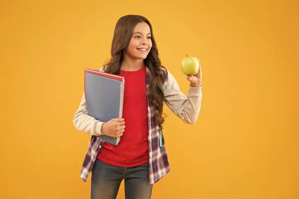 Szczęśliwy nastolatek szkoły trzymać książki i witaminy żółte tło, odżywianie szkoły — Zdjęcie stockowe