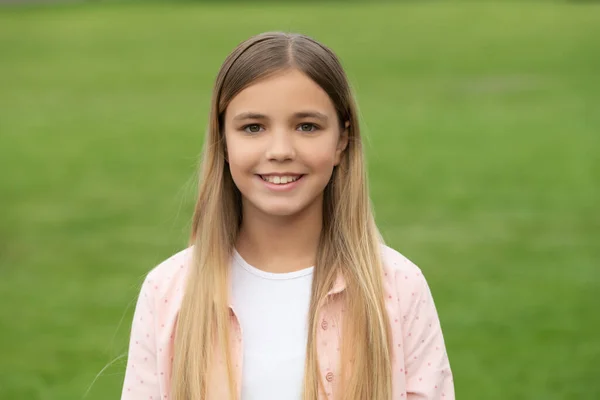 Gelukkig meisje kind glimlachen op groen gras achtergrond buiten — Stockfoto