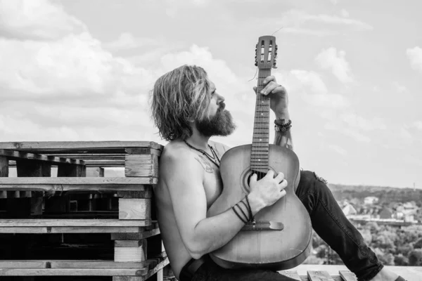 Красивий бородатий хлопець зі стильним волоссям грає на акустичній гітарі, струнному інструменті — стокове фото