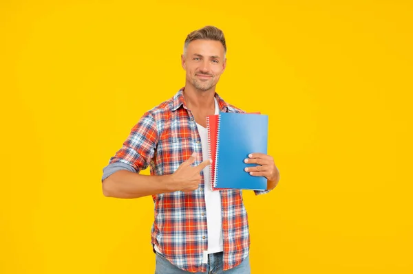 Happy guy étudiant pointant du doigt les livres fond jaune, éducation — Photo