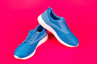 Pembe arka planda bir çift rahat mavi spor ayakkabı, yeni bir çift.