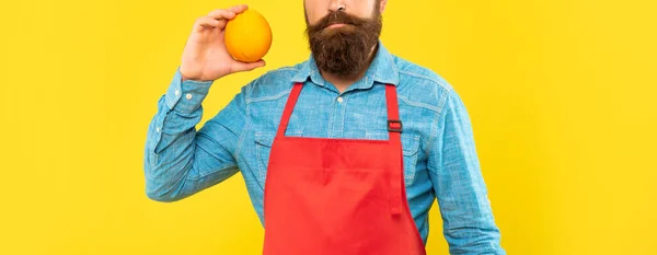 Σοβαρή άποψη των καλλιεργειών άνθρωπος σε κόκκινο ποδιά εκμετάλλευση νωπών πορτοκαλιών εσπεριδοειδών κίτρινο φόντο, φρούτων — Φωτογραφία Αρχείου