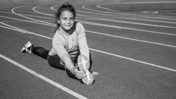 Κορίτσι παιδί προπόνηση αθλητισμού έξω στην αρένα γήπεδο κάθονται σε split, ευελιξία — Φωτογραφία Αρχείου