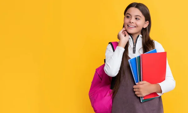 Estudante feliz com mochila escolar e caderno de trabalho no fundo amarelo — Fotografia de Stock
