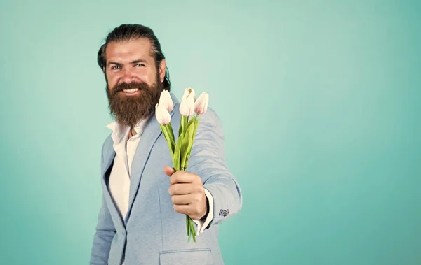 This is for you. hipster man hold tulip flowers. gift for romantic date. bearded man in elegant jacket hold flowers. wedding day. happy fathers day. mature bride groom with bouquet