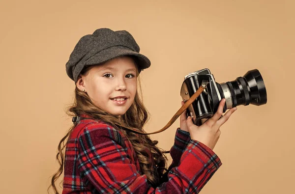 Vrolijk kind in hoofddeksel en geruite jas gebruik vintage camera, retro fotograferen — Stockfoto