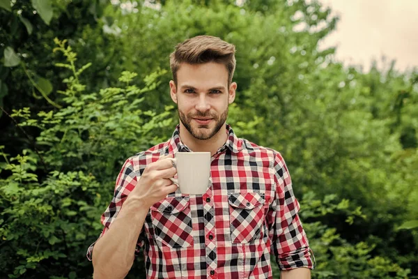 체크무늬 셔츠를 입은 잘생긴 청년은 아침에 커피를 마십니다. — 스톡 사진