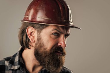 Sakallı ve bıyıklı yakışıklı adam miğfer takıyor, korunuyor.