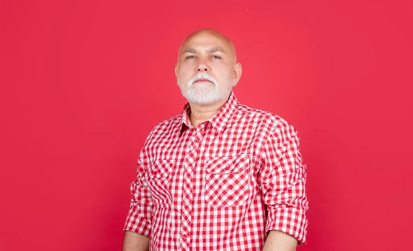 Serious senior man or grandfather in checkered shirt on red background — Stock Photo, Image