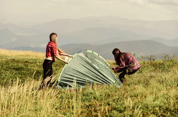 Fetele au ridicat cortul pe vârful muntelui. Conceptul abilităților de camping. Camping şi drumeţii. În mijlocul pustietăţii. Locuinţe temporare. Vacanță în munți. Camping trip. Ajutor pentru a avea partener pentru ridicarea cortului — Fotografie, imagine de stoc