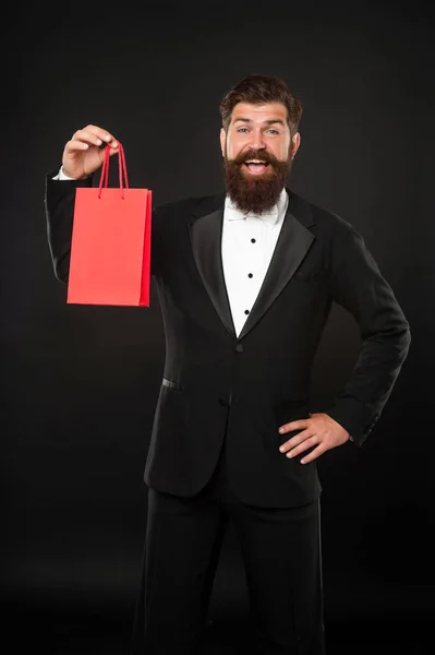 Surprised man in tuxedo bow tie on black background with purchase shopping bag. copy space. — ストック写真