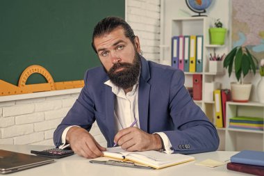 Çok iş var. gayri resmi eğitim. Erkek öğrenci ders sırasında sınıfta oturur. Sınavı geç. Konuyu öğrenmek. Okula dönüyorum. Öğretmenler günün kutlu olsun. Sakallı vahşi adam kostüm giyiyor.