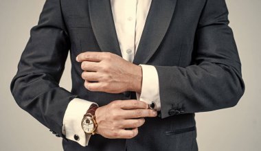 Bilekliğinde bilekliği olan kırpık bir adam resmi moda smokinli, moda aksesuarlı bir erkek kol saati.