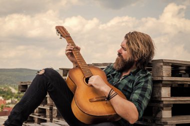 Tişörtlü, beyaz, vahşi hippi akustik gitar ve müzik çalıyor.