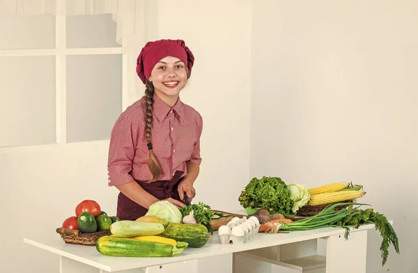 Åtog sig att god mat. Barnet bär kockuniform. barn i hatt och förkläde. kock med grönsaker — Stockfoto