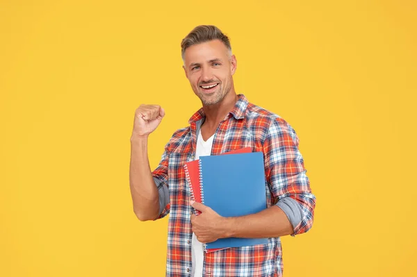 Professeur homme excité faisant geste gagnant tenant des livres fond jaune, éducation — Photo