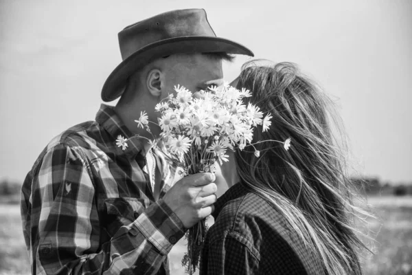 Casal apaixonado por homem e mulher beijando atrás daisy buquê em camomila campo de flores, romance. — Fotografia de Stock