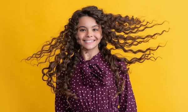 Felice ragazza con lunghi capelli ricci bruna su sfondo giallo — Foto Stock