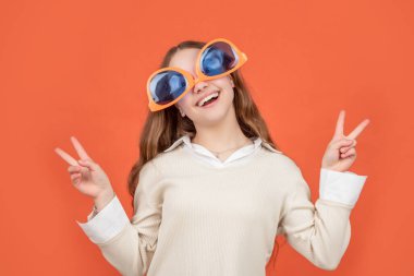 Mutlu kız ters dönmüş komik güneş gözlüğü takıyor Ziyaretçi şarkıları söylüyor kahverengi arka plan, zafer