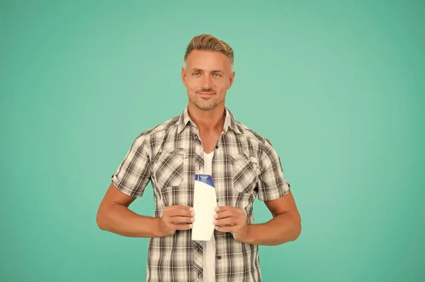 Chico mantenga la botella de cabello para hombre champú azul espacio de copia de fondo, cuidado de la piel — Foto de Stock