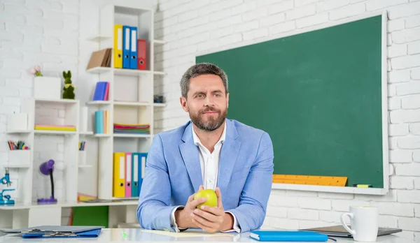School teacher hold apple in classroom at blackboard — ストック写真