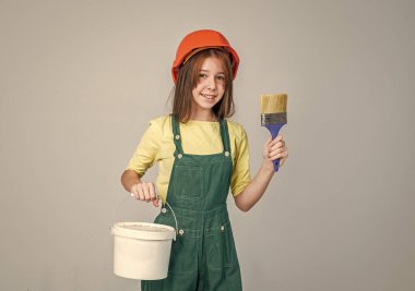 İş bittikten sonra. Miğferli kız müteahhitlik yapıyor. İnşaat ve yenileme. Çocuk inşaat yapıyor. Mühendis genç inşaat işçisi. Uluslararası İşçi Günü. ressam çalışma araçlarını kullanır