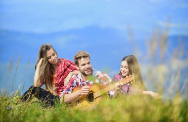 Yakışıklı adam gitar çalarken insanlar dağın tepesinde dinleniyor. Birlikte şarkı söylemek. Müzikal duraklama. Yürüyüş eğlencesi. Huzurlu bir yer. Doğanın melodisi. Yürüyüş geleneği. Müzik eşliğinde yürüyüş yapan arkadaşlar.