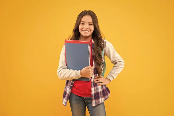 Gelukkig kind terug naar school holding studieboeken gele achtergrond, kennisdag — Stockfoto
