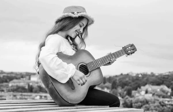 Щаслива дівчина-підліток грає на акустичній гітарі на фоні неба, музика — стокове фото