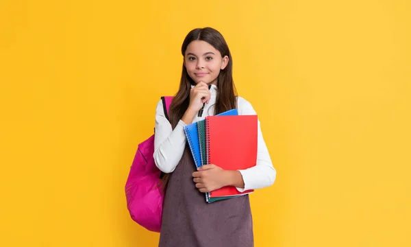 Happy child with school rucksack and workbook on yellow background — Stock Photo, Image