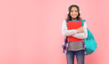 Çocukluk gelişimi. Kulaklıklı çocuk çalışma kitabını ve sırt çantasını tut..