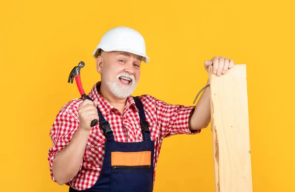 Glücklicher älterer Herr Holzarbeiter im Helm auf gelbem Hintergrund — Stockfoto