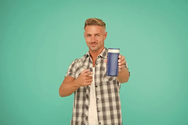 Hombre señala con el dedo el fondo azul de la botella de gel. Gel de baño. Promoción de productos de baño para hombre, espacio de copia. — Foto de Stock