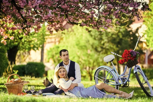 Passionerad kärlek. lyckliga par förälskade. kvinna och man ligger i parken och njuter av dagen tillsammans. Alla hjärtans dag picknick. romantisk picknick i parken. par datum på filt under Sakura blommor. camping — Stockfoto