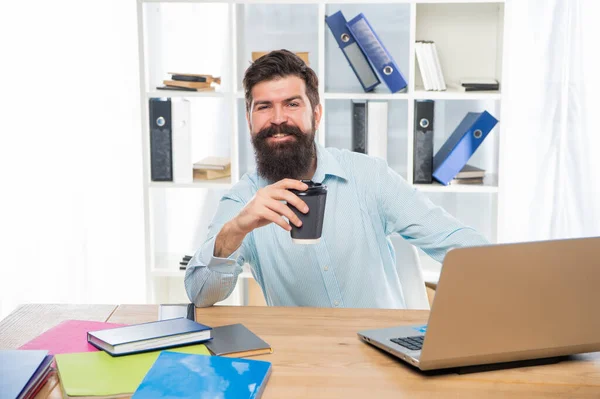 Feliz hombre de negocios bebiendo café para llevar sentado en el escritorio de la oficina, pausa para el café — Foto de Stock