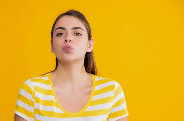 Молода дівчина в літній смугастій сорочці на жовтому тлі. поцілунок — стокове фото