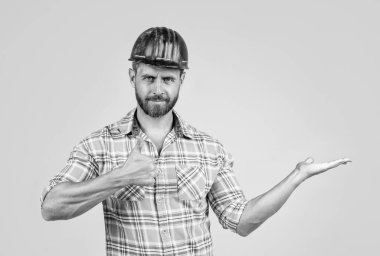 İnşaat kasklı yakışıklı ustabaşı ve inşaat alanında kareli gömlek. Ürün sunumu, fotokopi alanı, en iyi servis.