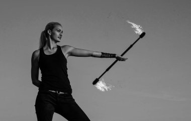 Kendine güveni tam seksi bir kadın tehlikeli ateş gösterilerinde alevli baston çeviriyor açık havada mavi gökyüzü, cesur