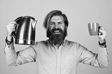 İyi günler dilerim. Sıcak çay iç. Sakallı adam mağaza asistanı mutfak aletlerini sunar. Oda servisinde kullanışlı. Olgun karizmatik erkek elektrikli su ısıtıcısı kullanır. Sakallı ve bıyıklı adam çay yapar.