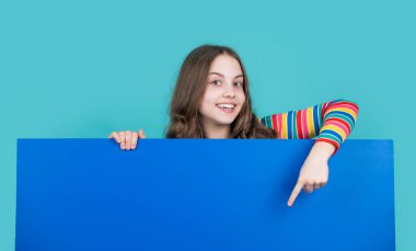 Gülümseyen çocuk reklam için fotokopi alanı olan boş mavi kağıdın arkasında