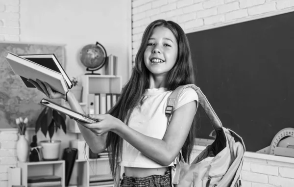 Šťastná holčička nosit batoh a knihy ve škole, zpět do školy — Stock fotografie