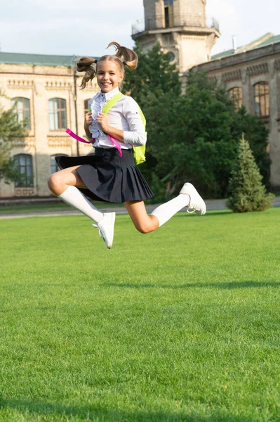 Gelukkig energiek meisje kind in uniform terug naar school springen voor vreugde, 1 september — Stockfoto