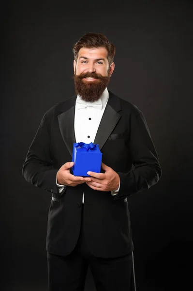 Uomo felice in smoking papillon formalwear su sfondo nero con confezione regalo. giornata di boxe — Foto Stock