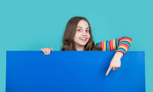 Usmívající se dítě za prázdný modrý papír s kopírovacím prostorem pro reklamu — Stock fotografie