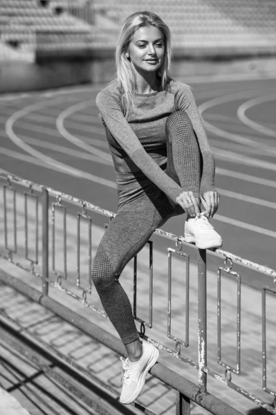 身穿运动服、体形性感的女子在体育场系鞋带，积极的一天 — 图库照片